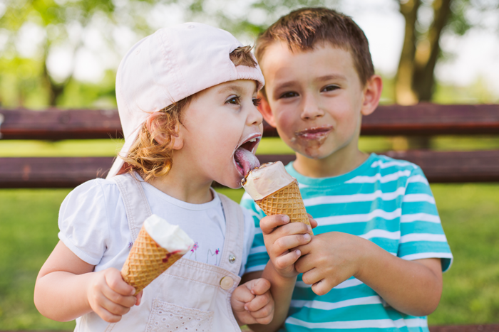 children eating ice cream cones on a park bench